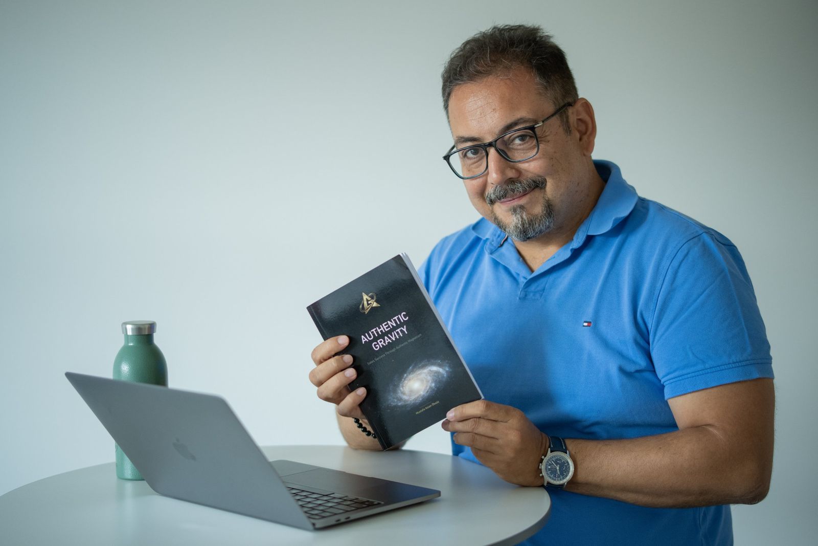 Mustafa Aslan Öksüz mit dem Buch Authentic Gravity am Laptop